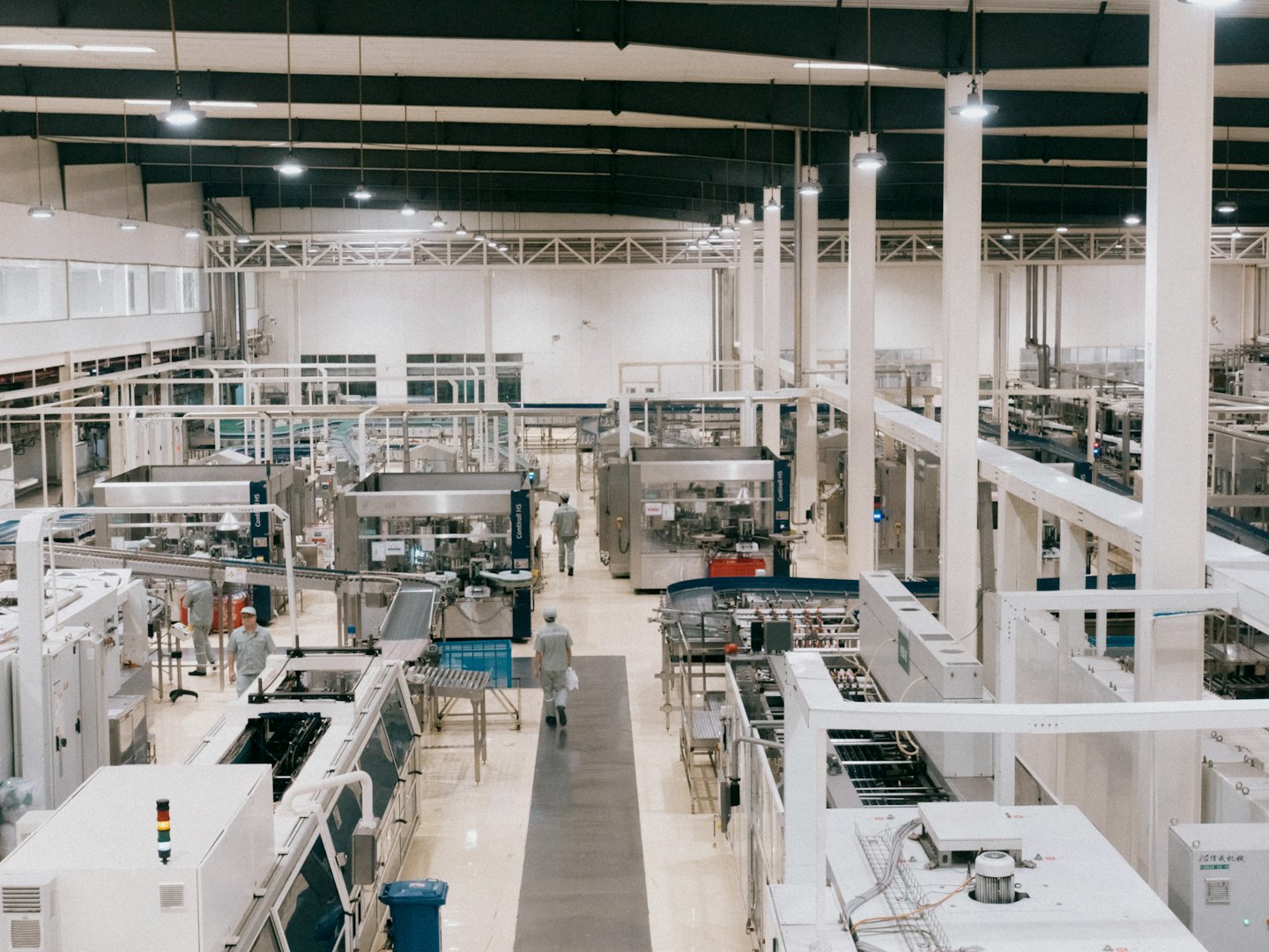 Arbeiter bewegen sich zwischen automatisierten Maschinen auf einer Produktionslinie.